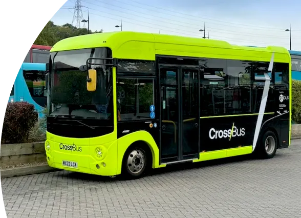 Photo of CrossBus at the bus station. The bus has a volt green and black livery, with the CrossBus logo in white and volt green on the side.