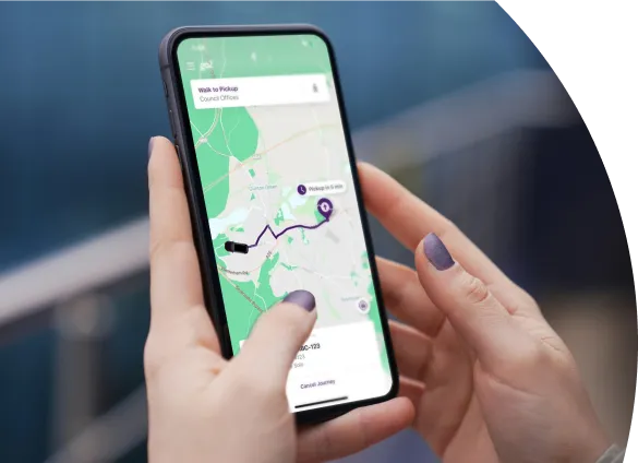 Hands holding a phone, using an app. The app is the Go2 app booking a CrossBus. The hands have lilac nails. The background is blurred.
